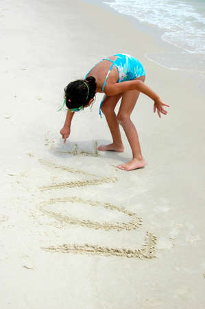 Girl on the beach writting on the sand