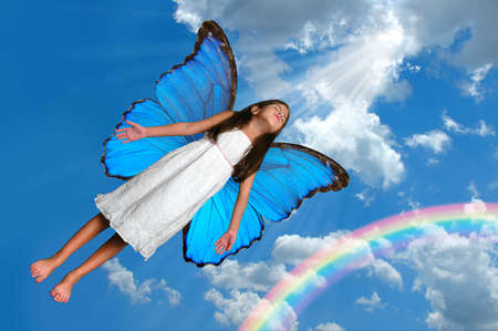 Fairy with butterfly wings flying with rainbow in background.の写真素材