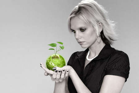 Woman holding the earth with plant over a neutral background.の写真素材