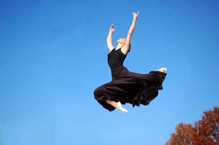 Ballerina in black outfit jumping outdoorsの写真素材