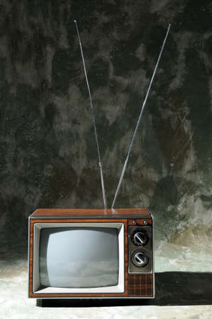 Vintage TV with knobs and antenna over a textured backgroundの写真素材
