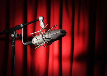 Vintage microphone with spotlight over a red curtainの写真素材