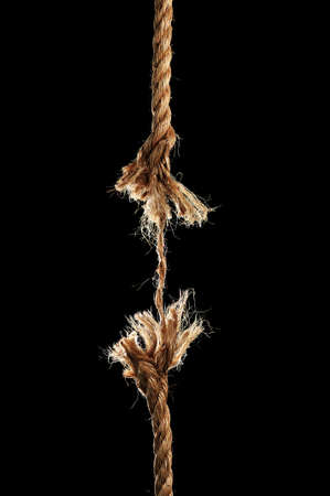 Taut rope breaking apart isolated over a black background