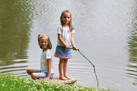 Young girls playing by a lakeの写真素材