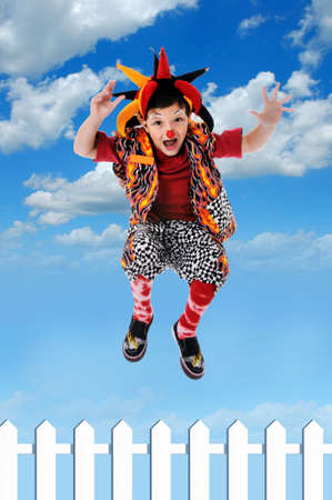 Child clown jumping fence with sky and clouds background