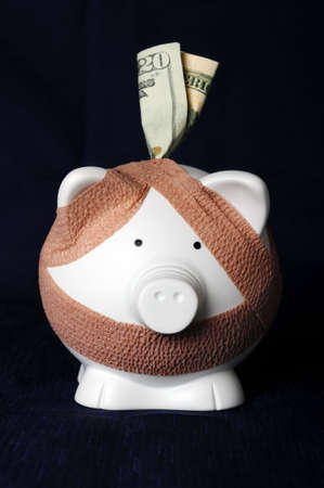 Piggy bank with bandages over a dark backgroundの写真素材