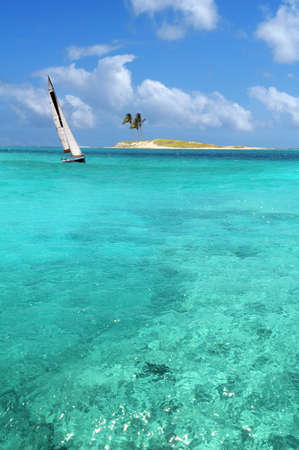 Sailboat sailing on crystal clear waters with island in backgroundの写真素材