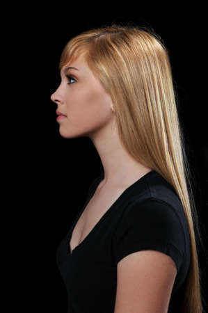 Profile portrait of beautiful teenage girl over a black backgroundの写真素材