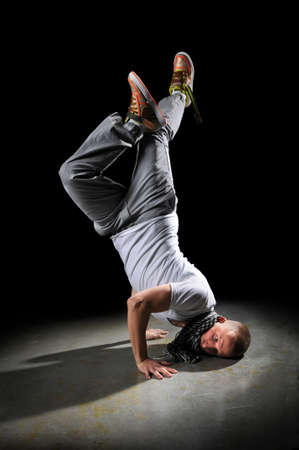 Young breakdancer performing free-style dancing over dark background