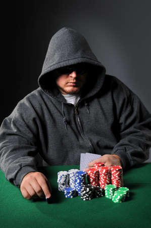 Poker player holding chip staring through sunglassesのeditorial素材