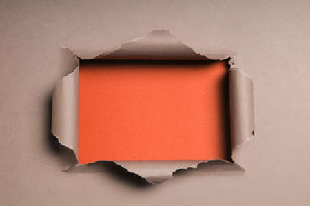 Beige paper ripped to form a rectangle over orange paper in backgroundの写真素材