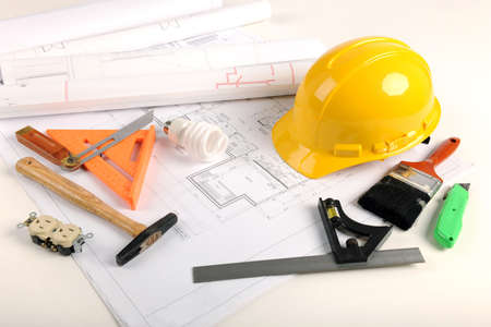 Architectural plans, hardhat and tool over draft table