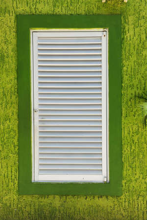 Window over bright green textured wall in Cozumel Mexico