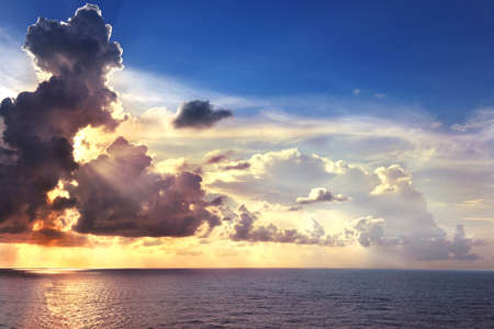 Sunset at sea with clouds and reflections on the waterの写真素材