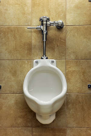 Public urinal over tiled wall