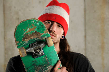 Portrait of young man holding grunge skateboard
