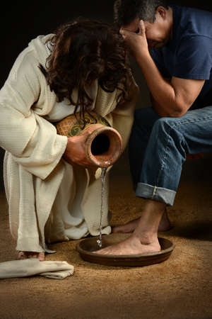 Jesus washing feet of man wearing jeansの写真素材