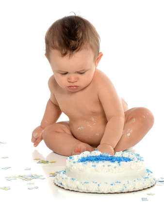 Hispanic boy reaching for birthday cake isolated over white backgroundの写真素材