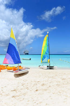 Boats for rent on Caribbean beach with cruise ship in background
