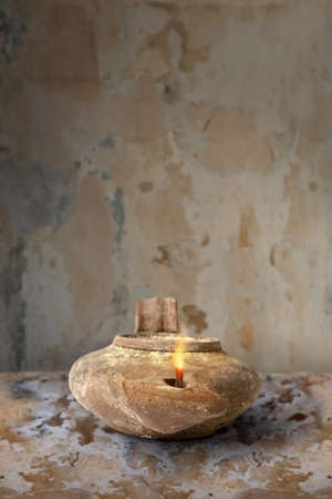 Ancient Middle Eastern oil lamp on clay surfaceの写真素材