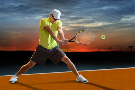 Mature Hispanic tennis player swinging racket at sunsetの写真素材