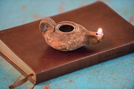 Ancient lamp on Bible over old table