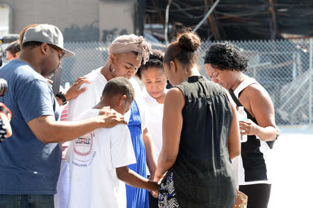 FERGUSON, MO/USA â AUGUST 15, 2015: People pray at the Site of Quick Trip Holds sign after Police Chief Thomas Jackson release of the name of the officer that shot Michael Brown.のeditorial素材