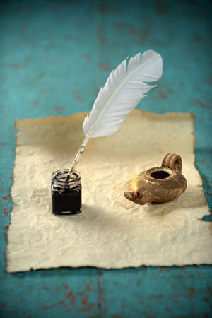 Inkwell and ancient lamp over paper on vintage tableの写真素材