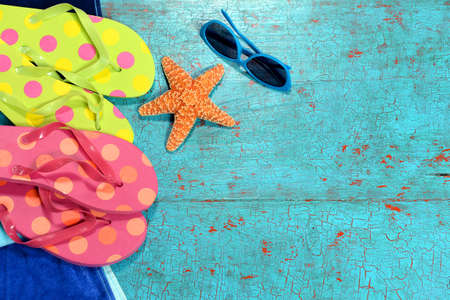 Summer background with flip-flops, starfish and sunglasses over painted wood planksの写真素材