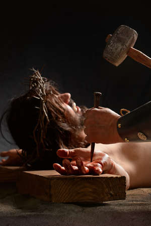 Jesus hand being nailed to the cross by Roman soldierの写真素材
