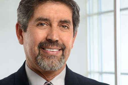 Portrait of Hispanic businessman smiling with office window in background