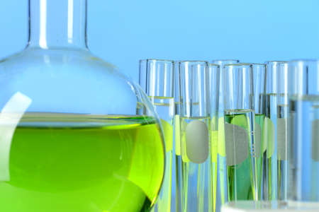 Laboratory glassware filled with colored liquids over blue background