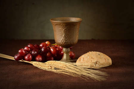 Cup of wine, red grapes, bread and wheat as symbols of Communion