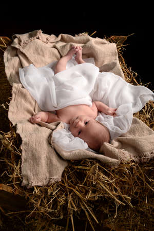 Jesus resting on a manger over dark backgroundの写真素材
