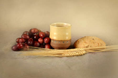 Communion table with cup of wine, grapes, bread and wheatの写真素材