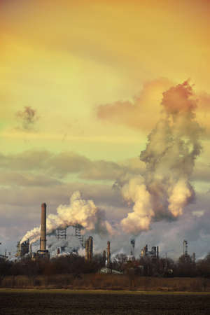 Oil refinery spewing gases from smoke stacks at sunsetのeditorial素材