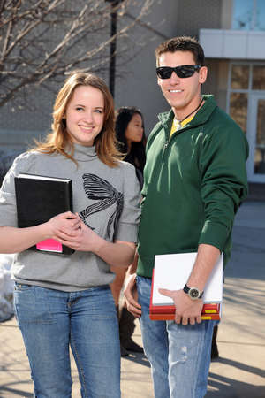 College students holding textbooks outside during sunny dayの写真素材