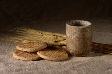 Wine and bread with wheat over vintage table cloth