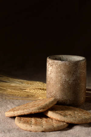 Symbols of communion: cup of wine, wheat and bread over table clothの写真素材