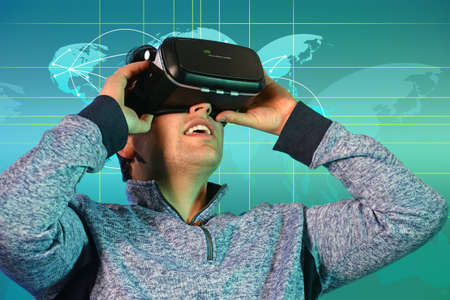 Portrait of young man using virtual reality glasses with world map in backgroundの写真素材