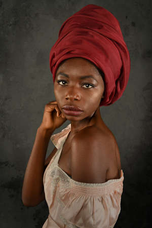 Young African woman with red turban over gray backgroundの写真素材