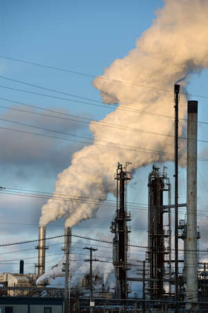 Smokestacks from oil refinery releasing thick smoke into the atmosphere