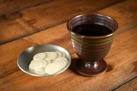 Communion wafers and cup of wine on wooden tableの写真素材