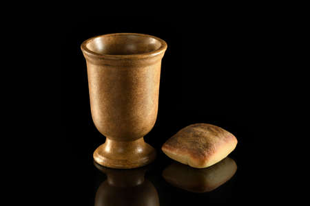 Cup of wine and bread on reflective table over dark backgroundの写真素材