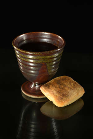 Cup of wine and bread on table over dark backgroundの写真素材