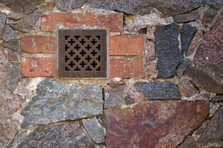 Grunge old bricklaying wall fragment from red bricks and small window . Red and grey background. Ventilation window.の写真素材