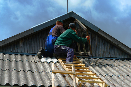 Workers are changing the old window on the roof. Old wooden house. Detail.の写真素材