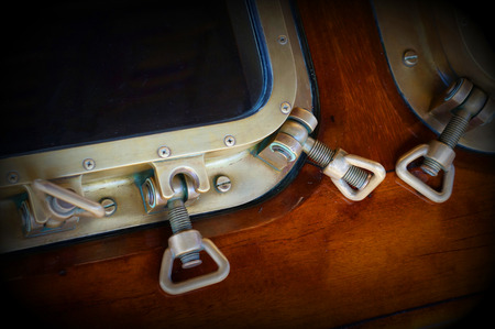 Old cruise ship window details in the evening. yacht window fragment. Vintage background. Non-ferrous metal parts. Technical aesthetics.の写真素材