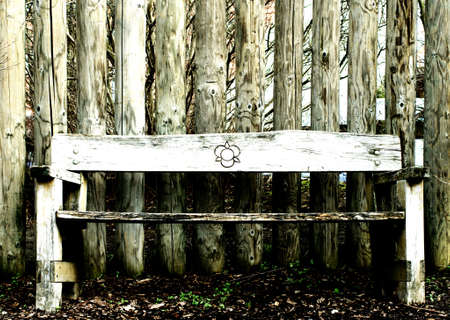 The front view on a park-bench before a wall with round planks                 