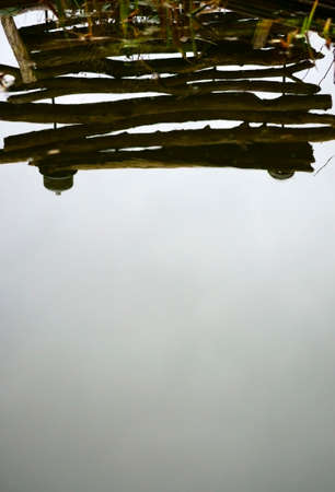 The photograph of a garden pond in which a stack of wood is reflected             の写真素材